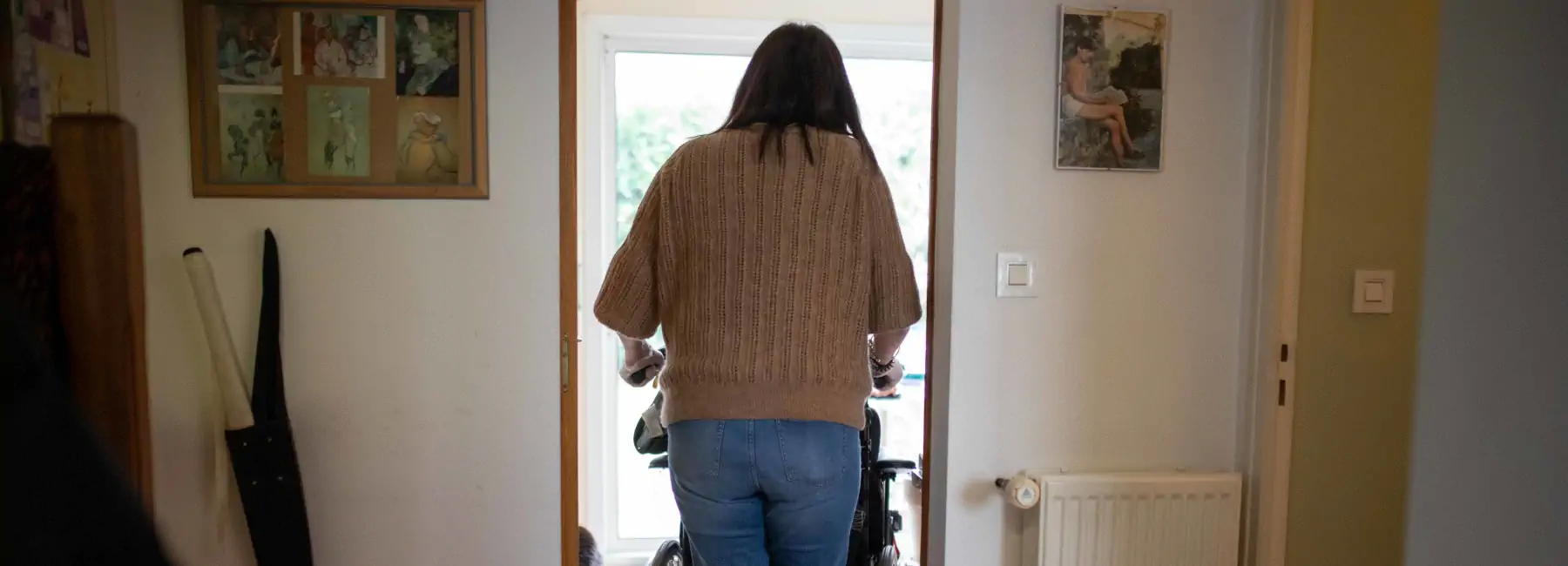 Femme de dos poussant un fauteuil roulant
