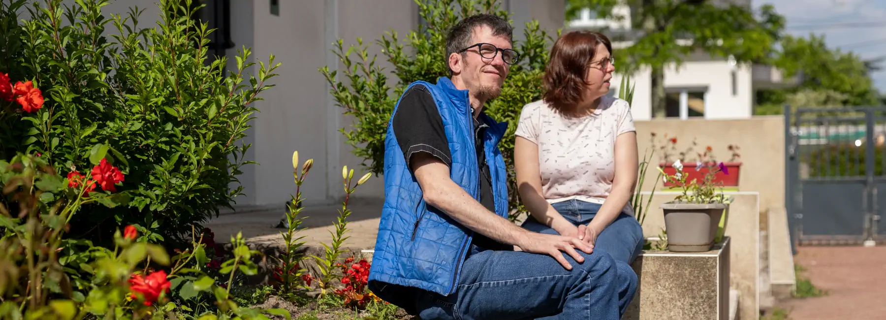Couple assis devant un parterre de fleurs