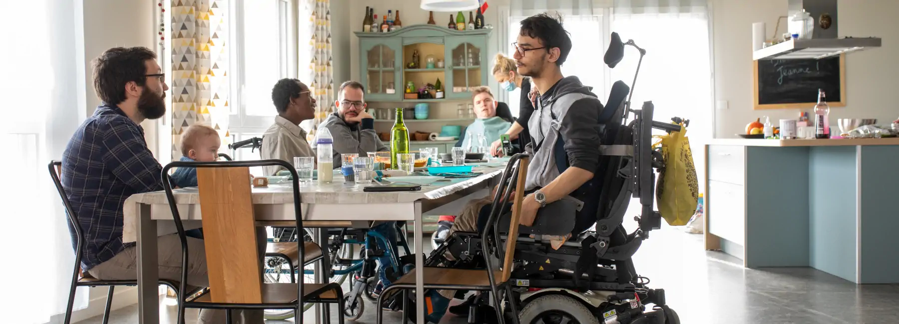 Groupes de personnes en fauteuil autour d'une table lors d'un repas
